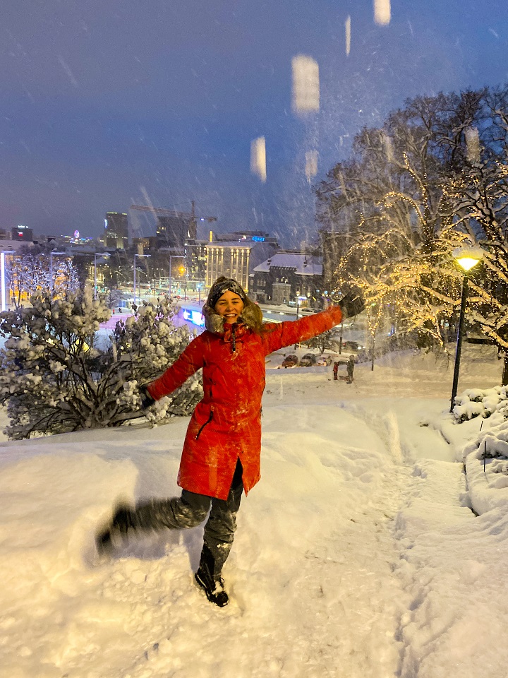 Eine Frau in rotem Mantel wirft Schneebälle.