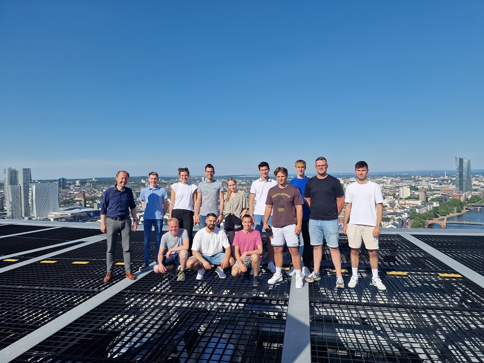 Eine Gruppe Menschen steht auf einem Gebäude. Sie genießen den Ausblick und die gemeinsame Zeit.