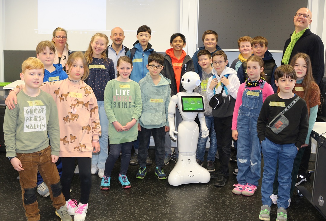 Eine Gruppe von Kindern und Erwachsenen posiert für ein Foto mit einem Roboter.