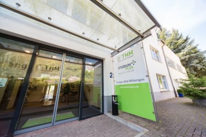 Der Eingang zum Gebäude mit einem grünen Schild.