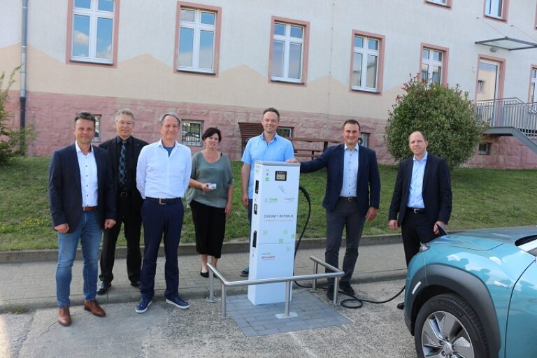 Personen stehen neben einem Auto, das gerade aufgeladen wird.