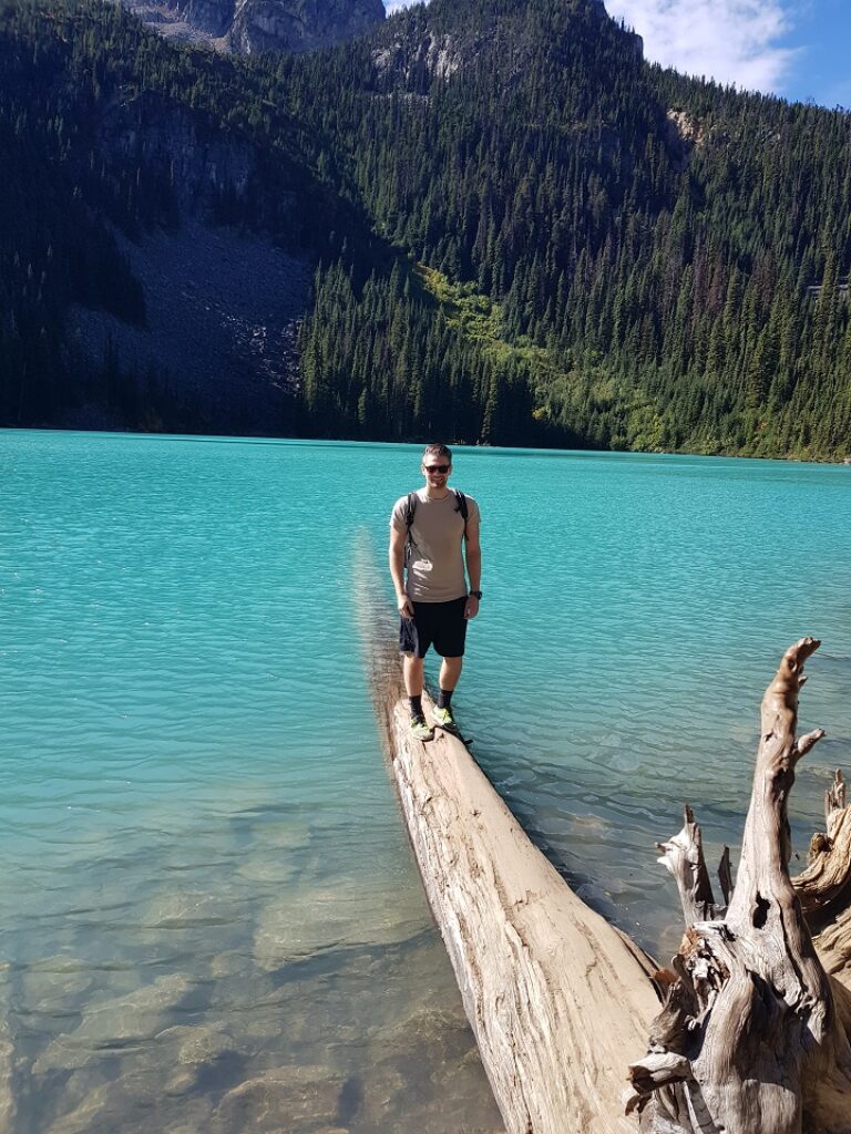 Ein Mann steht auf einem Baumstamm in einem See.