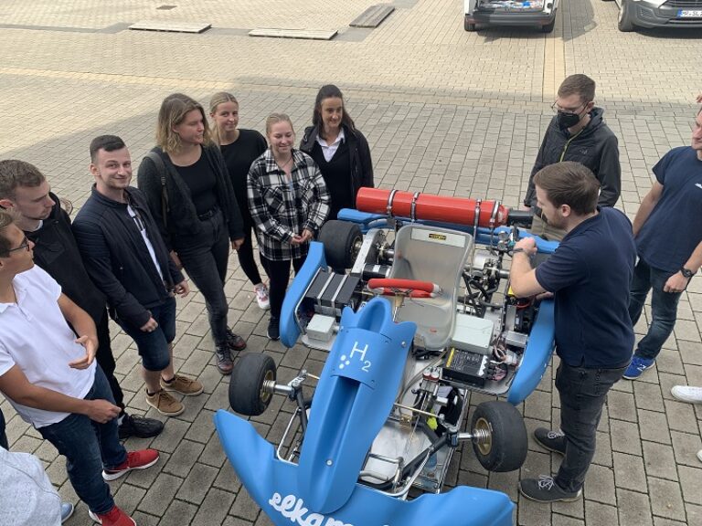 Eine Gruppe von Menschen steht um einen blauen Wagen herum.