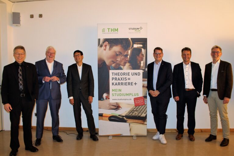 Eine Gruppe Männer steht vor einem Banner.