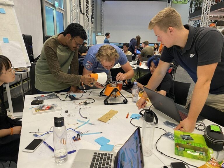 Eine Gruppe von Personen arbeitet an Elektronik an einem Tisch.