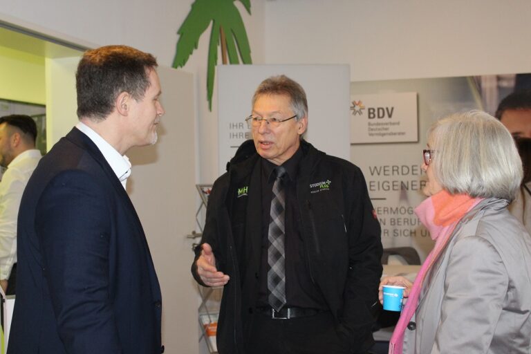 Zwei Männer und eine Frau unterhalten sich bei einer Veranstaltung.