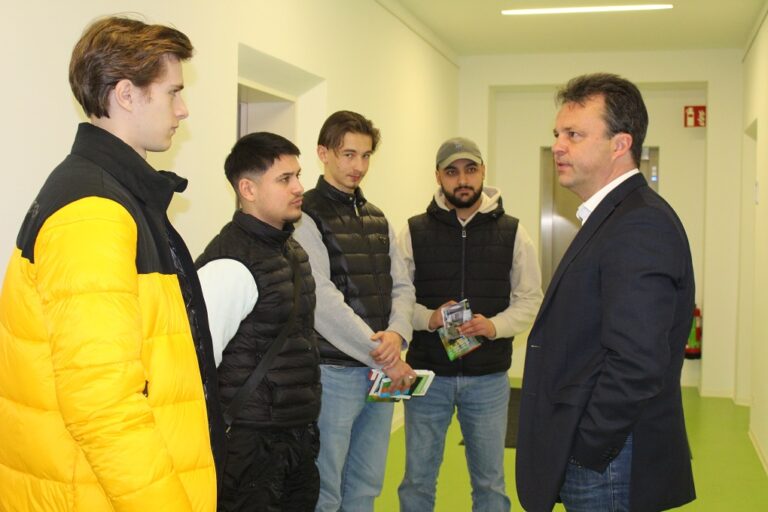 Eine Gruppe Männer steht in einem Flur und unterhält sich.