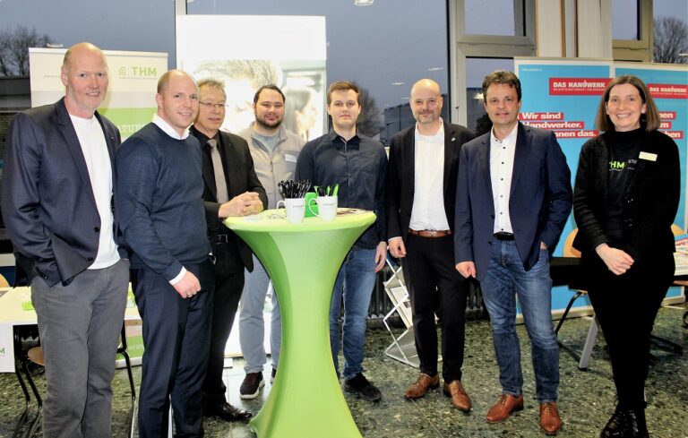 Eine Gruppe Menschen steht um einen grünen Tisch.