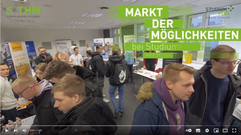Eine Gruppe von Menschen steht in einem Raum mit weißen und gelben Schildern.