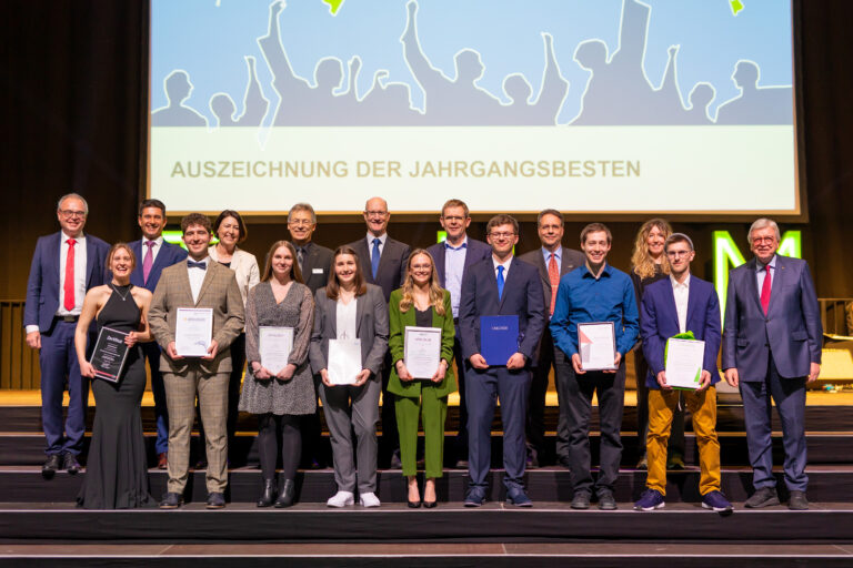 Eine Gruppe von Absolventen posiert auf der Bühne für ein Foto bei der Abschlussfeier.
