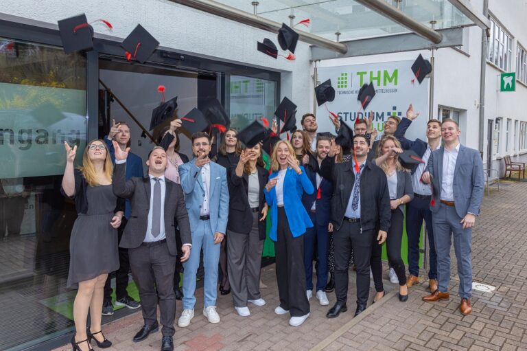 Eine Gruppe von Personen in Businesskleidung steht vor einem Gebäude.