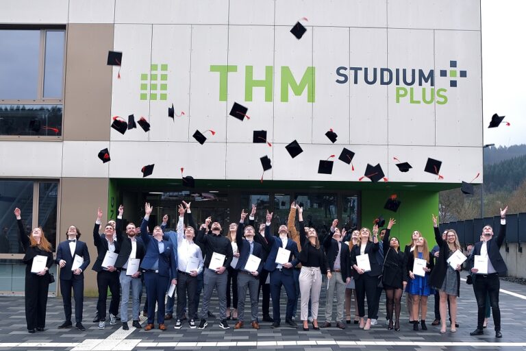 THM-Studenten feiern ihren Abschluss. Glückliche Absolventen in ihren Roben und Hüten.