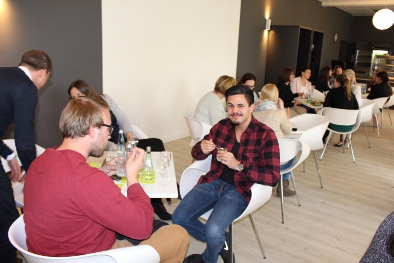 Menschen sitzen an Tischen in einem Restaurant und essen.