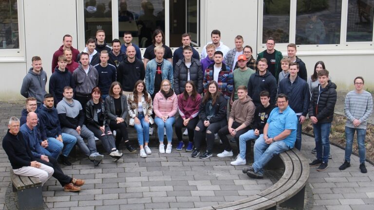 Eine Gruppe Menschen posiert vor einem Gebäude für ein Foto.