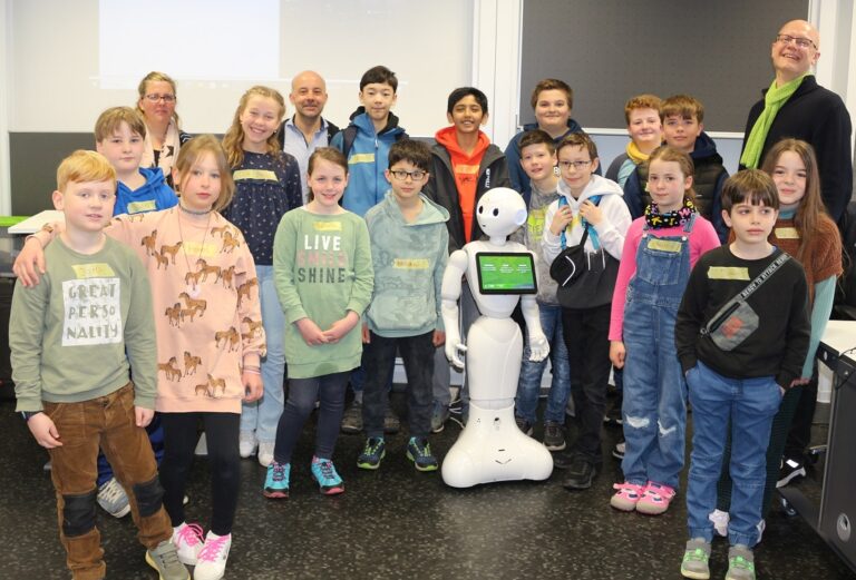 Eine Gruppe von Kindern und Erwachsenen posiert für ein Foto mit einem Roboter.