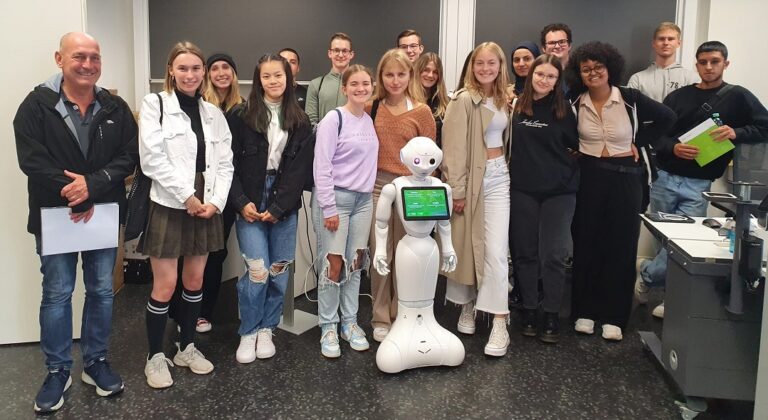 Eine Gruppe von Menschen steht vor einem Roboter.