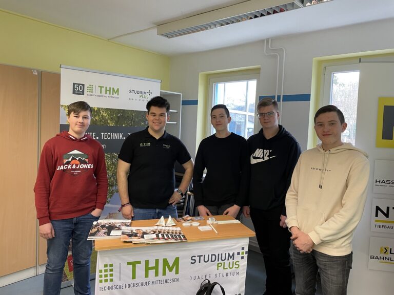 Fünf Studenten stehen um einen Tisch.