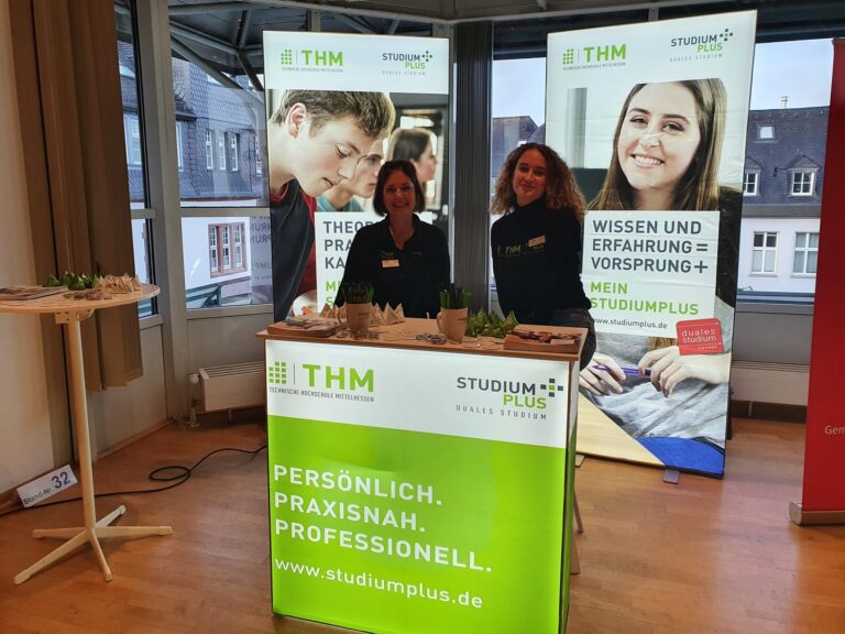 Zwei Frauen stehen hinter einem Tisch mit einem Banner.