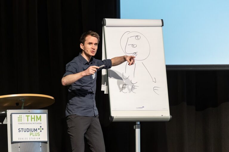 Ein Mann hält eine Präsentation auf einer Bühne.
