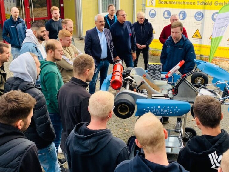 Eine Gruppe konzentrierter und interessierter Menschen steht vor einem Roboter.