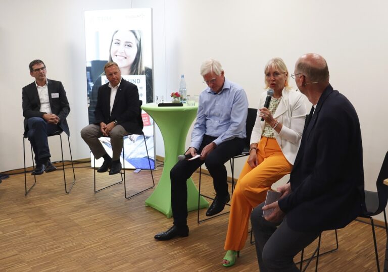 Eine Gruppe von Menschen sitzt auf Stühlen in einem Raum.