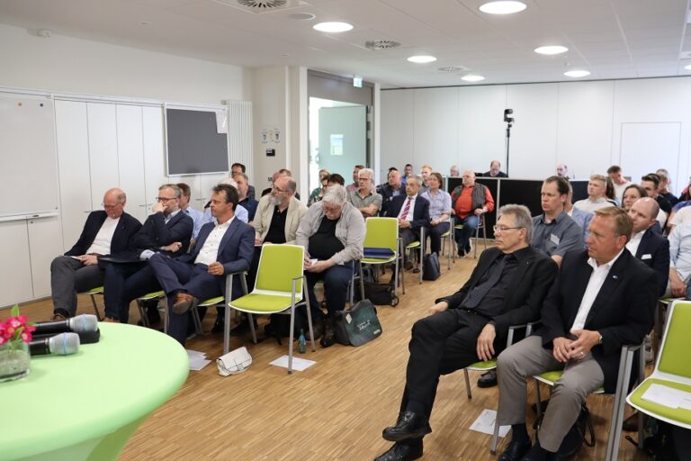 Eine Gruppe von Menschen sitzt in einem Raum auf Stühlen.