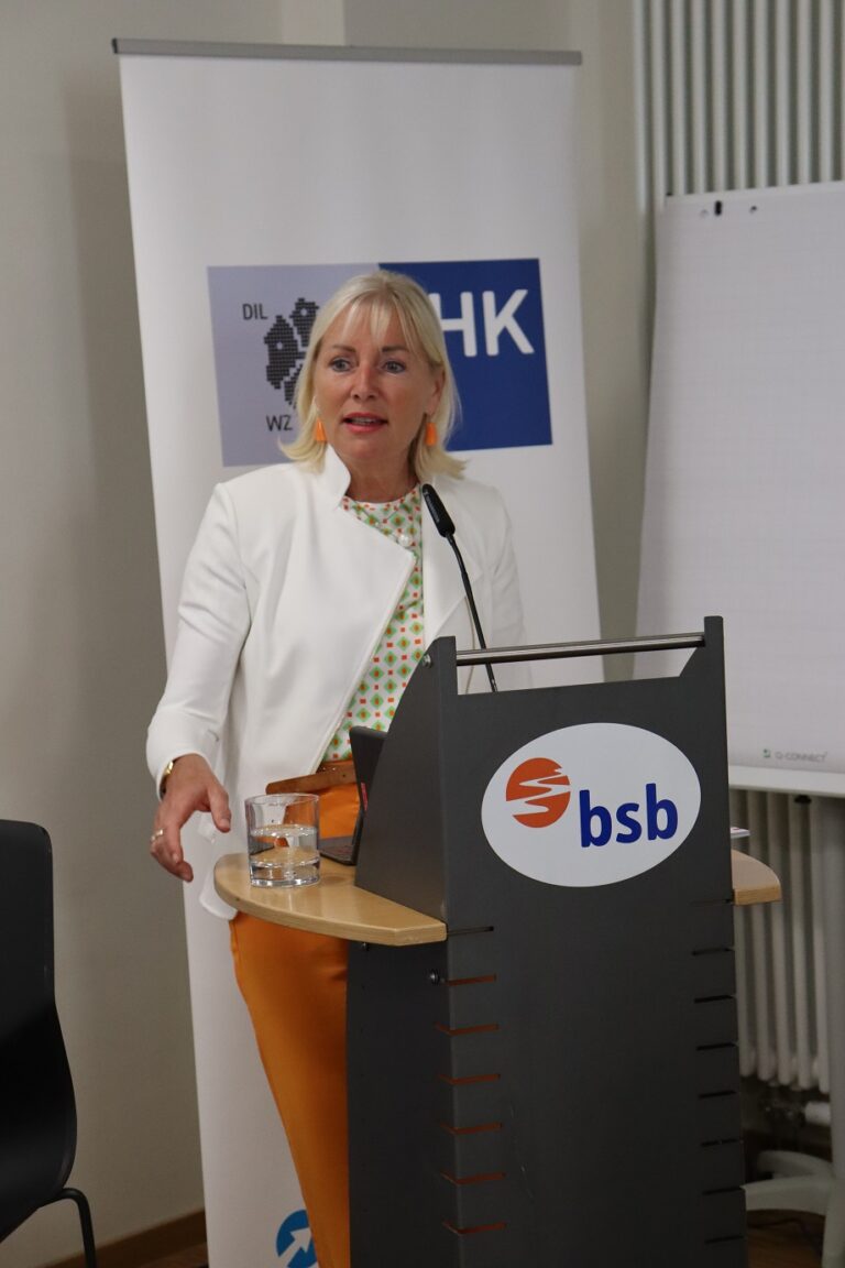 Eine Frau steht am Rednerpult und hält eine Präsentation.