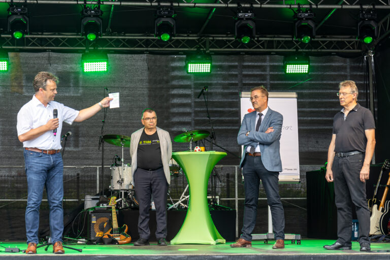 Eine Gruppe von Menschen steht auf einer Bühne mit grünem Licht.