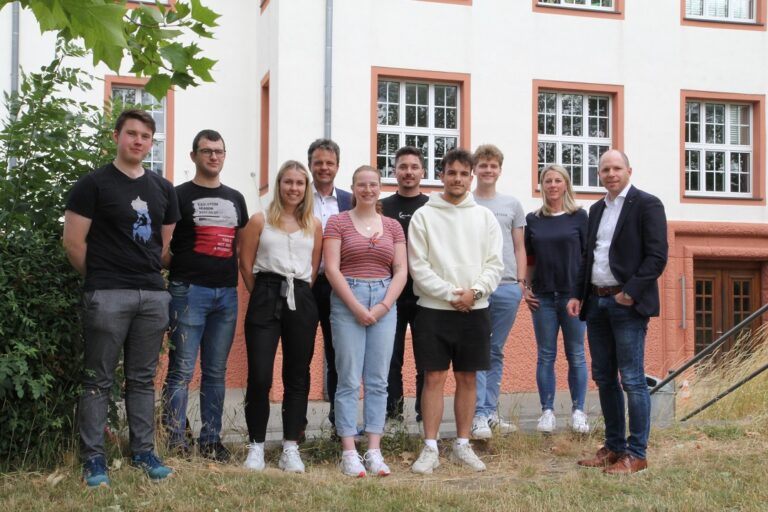 Eine Gruppe junger Leute steht vor einem Gebäude.