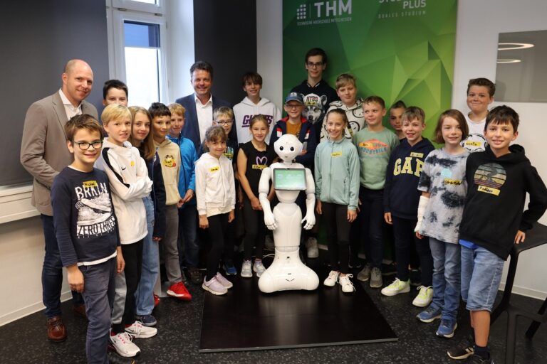 Eine Gruppe von Kindern und Erwachsenen posiert für ein Foto mit einem Roboter.