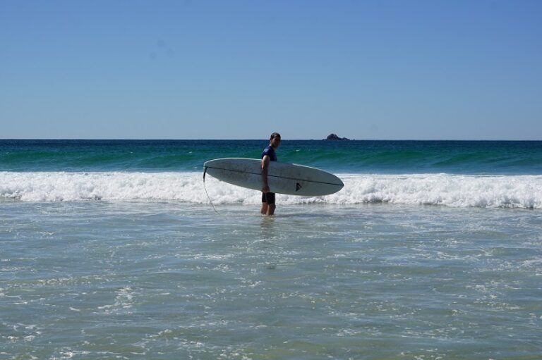 Ein Mann steht im Wasser mit einem Surfbrett.