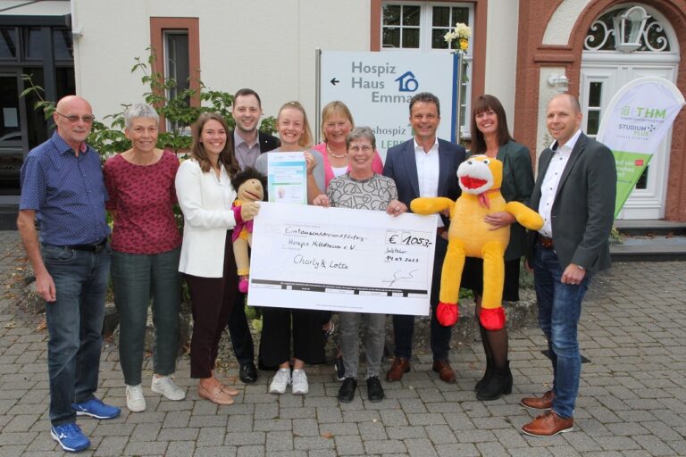 Eine Gruppe von Menschen hält einen Scheck. Sie lächeln und wirken glücklich.