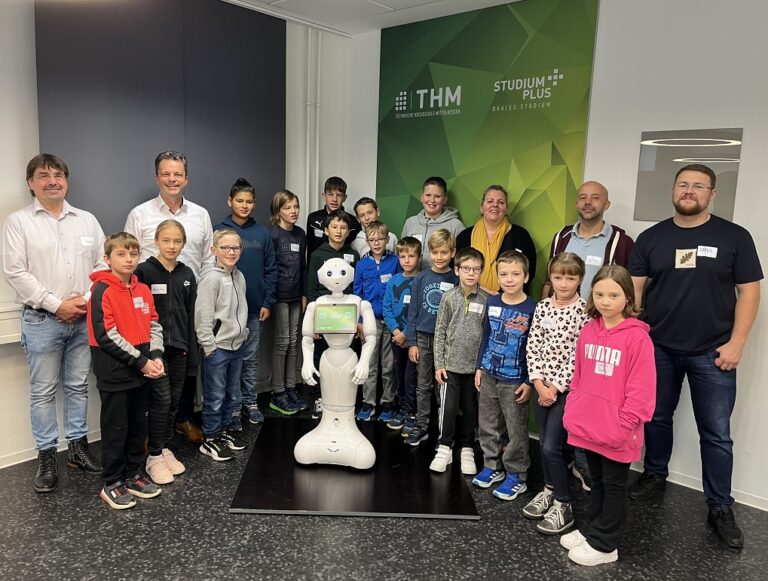 Eine Gruppe von Kindern und Erwachsenen posiert für ein Foto mit einem Roboter.