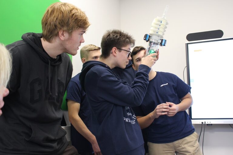 Schüler im Klassenzimmer mit einem Schüler, der einen Roboter hält.