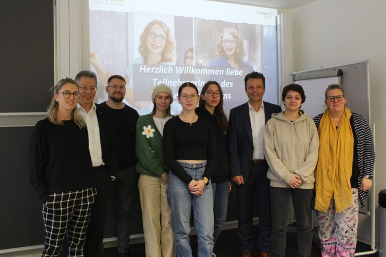 Eine Gruppe von Personen steht vor einer Präsentationswand.