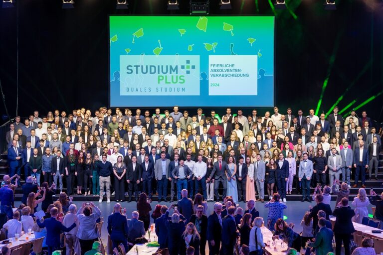 Eine Gruppe aus über 200 Studierenden freut sich auf einer Bühne