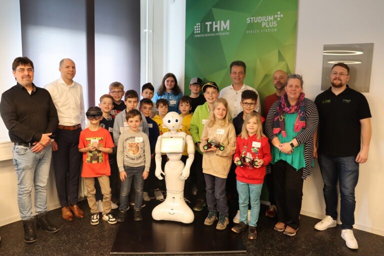 19 Kinder posieren mit dem Roboter Pepper fürs Foto