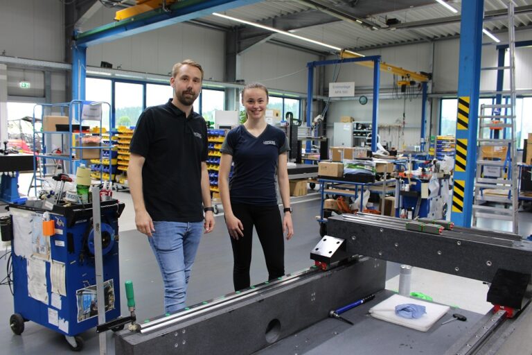 Christiana Lurch und Jens Fresen stehen vor einem Computertomographie-Manipulators in Portalbauweise.