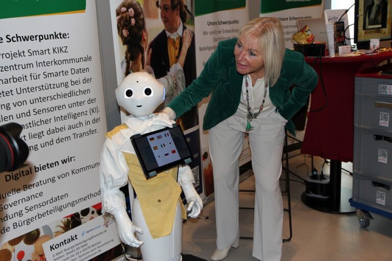 Die Digitalministerin beugt sich zu Roboter Pepper herunter.